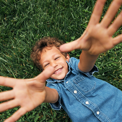 Smiling Boy in the Park Reaching Up To The Sky