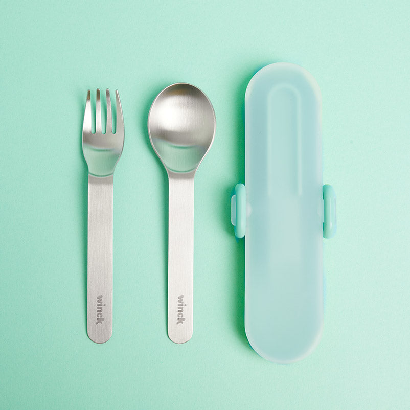 Winck Utensil Set in Pistachio which includes a stainless steel fork and spoon plus a carrying case, presented on a pale green background, embodying a sleek and functional design for convenient dining on the go.