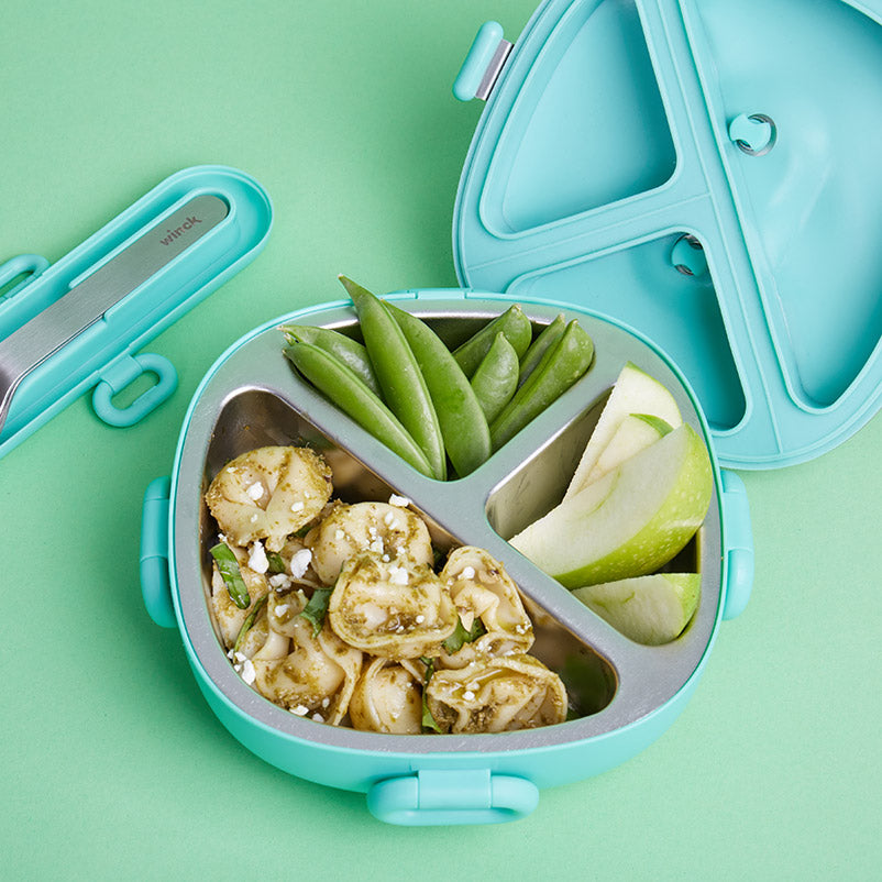 Winck Stainless Steel Bento Lunch Box in Pistachio. Lunch is packed and has a tasty pesto pasta, snap peas for a vegetable, green apple slices for a fruit. Winck to-go cutlery set in Pistachio is beside it. 