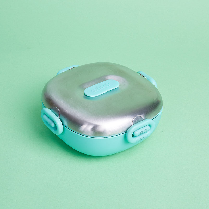Winck Stainless Steel Bento Lunch Box in Pistachio (colorway) with secure latches on a matching green background, perfect for kids' healthy meals.