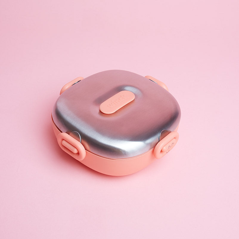 Winck Stainless Steel Bento Lunch Box in Peach on a matching pink background, highlighting the sleek design and kid-friendly features for a stylish, sustainable lunchtime option.